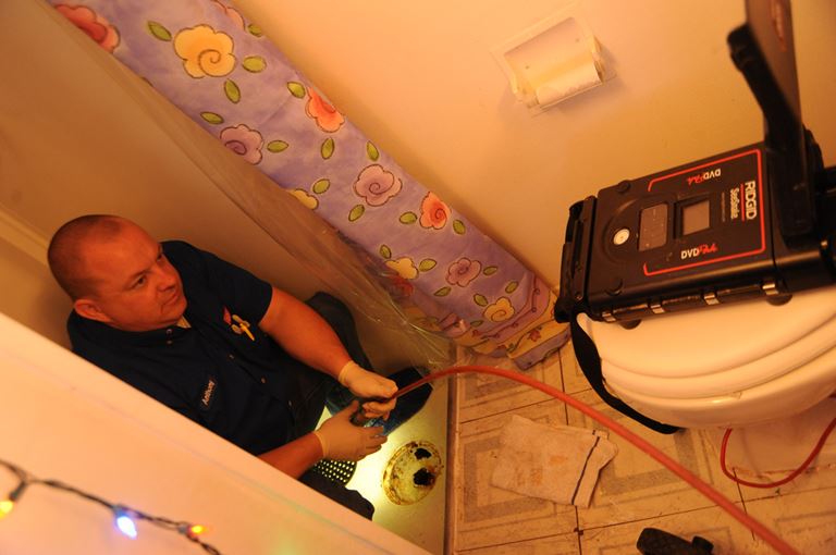 Plumber in bathroom monitors remote inspection camera